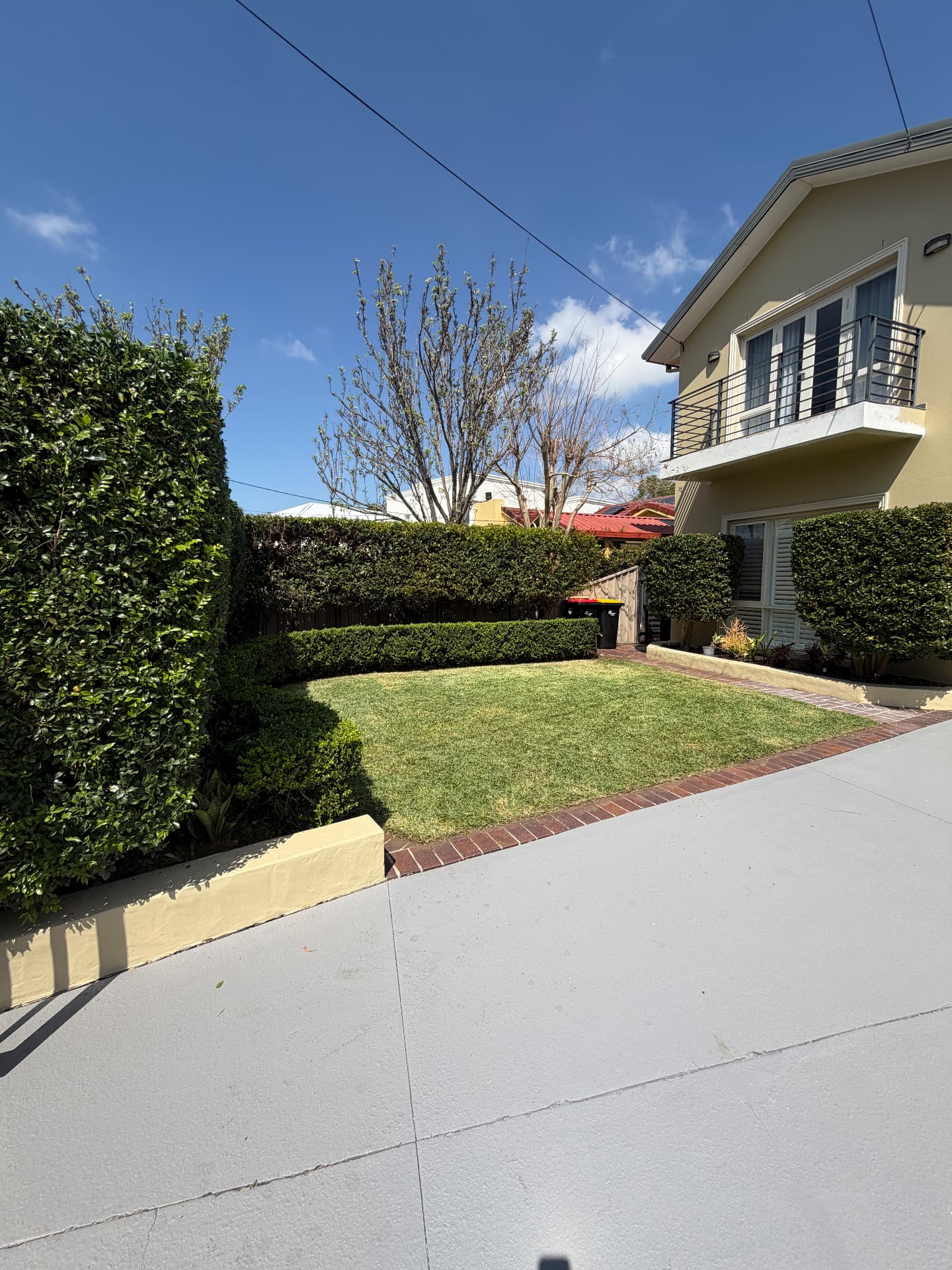 Trimmed hedges and box borders framing a small front lawn